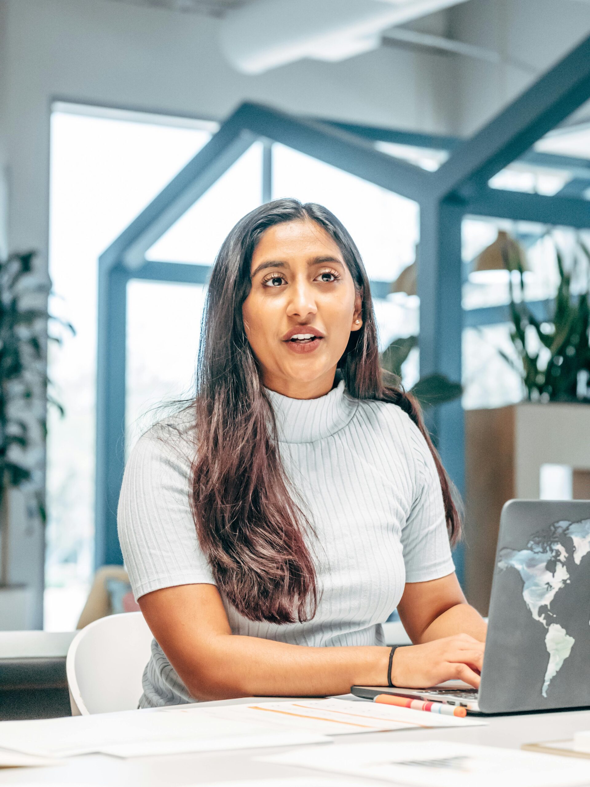 Confident professional woman working at a laptop in a bright modern office.